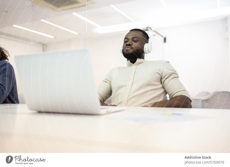 African American professional working with headphones african american man office laptop looking away corporate business desk technology modern workspace