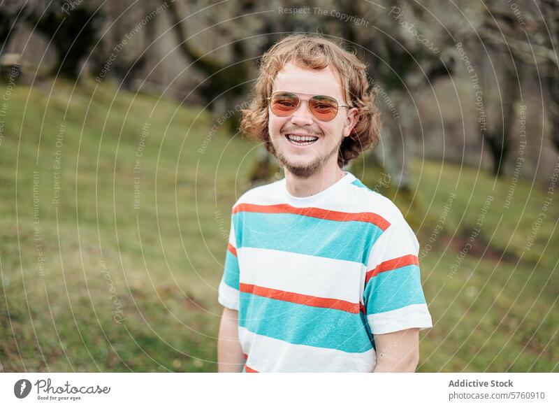A man with a warm smile stands outdoors, his casual style and carefree spirit embodying the joy of a day spent in nature portrait sunglasses cheerful happy