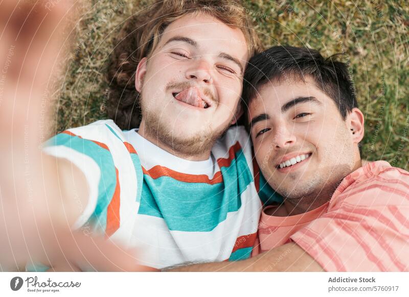 A tender moment of eye contact and smiles shared between a gay couple, both transgender, as they embrace on the grass love happiness lgbtq affection connection