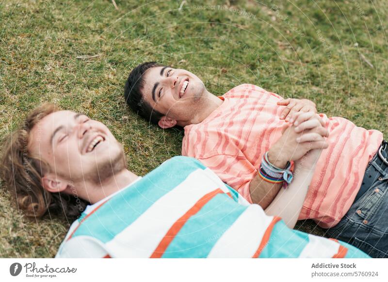 Two men, deeply in love and both transgender, enjoy each other's company, smiling and holding hands on a grassy field couple gay happiness joyful togetherness