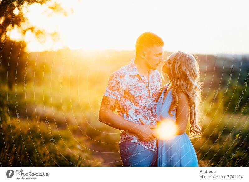 blonde girl with loose hair in a light blue dress and a guy in the light of sunset beauty boyfriend bride day engagement evening family fashion for a walk