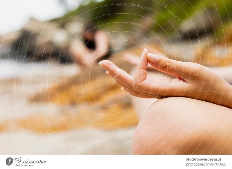 Hands of a young girl performing yoga asana pose on the beach meditating hands relaxation lifestyle woman exercise zen lotus wellness sitting real people