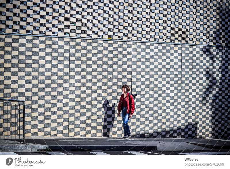 A young girl walks along the street in front of a checkerboard-patterned wall Girl Young woman Street chequered pattern checks brick Rectangle Wall (building)