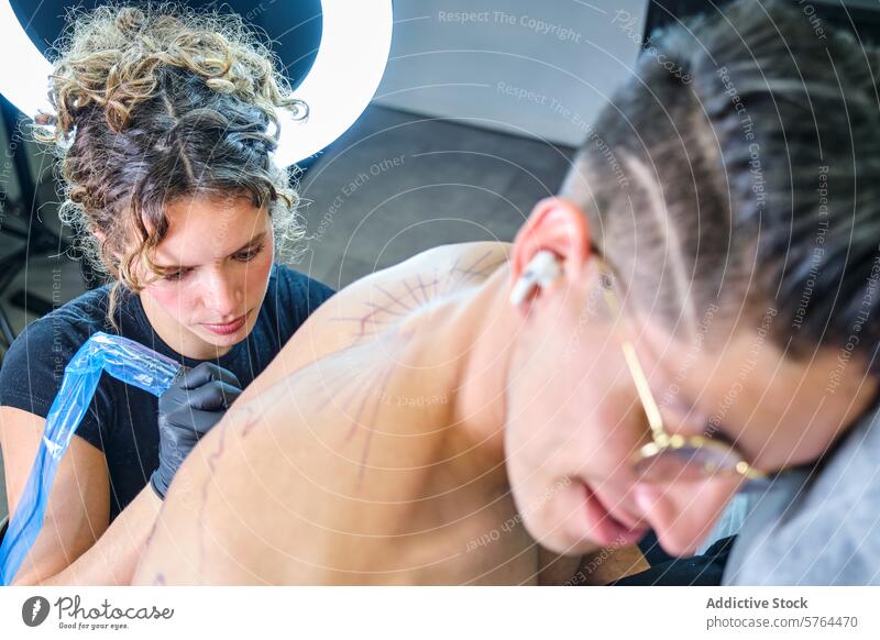 Female tattoo artist working on client in studio woman inking design shoulder tattooing professional artwork skin body art female creative craft skilled gloves