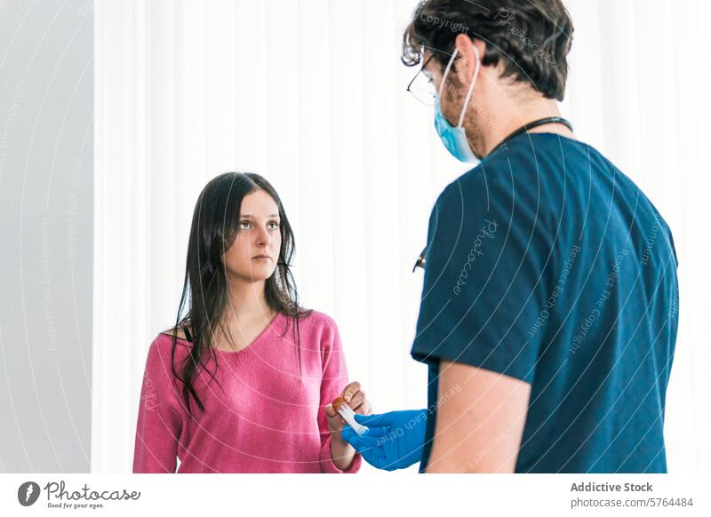 A healthcare professional in blue scrubs prepares a medical device with concentration as the patient looks on with a trusting gaze preparation clinic hospital