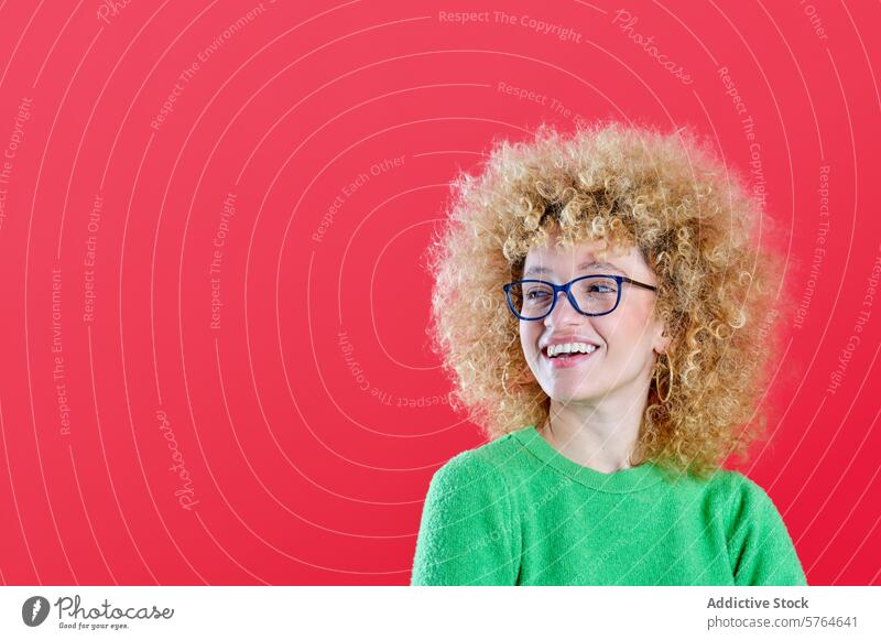 A cheerful woman with fluffy curly hair and eyeglasses is smiling off to the side, wearing a green sweater against a contrasting red background smile eyewear