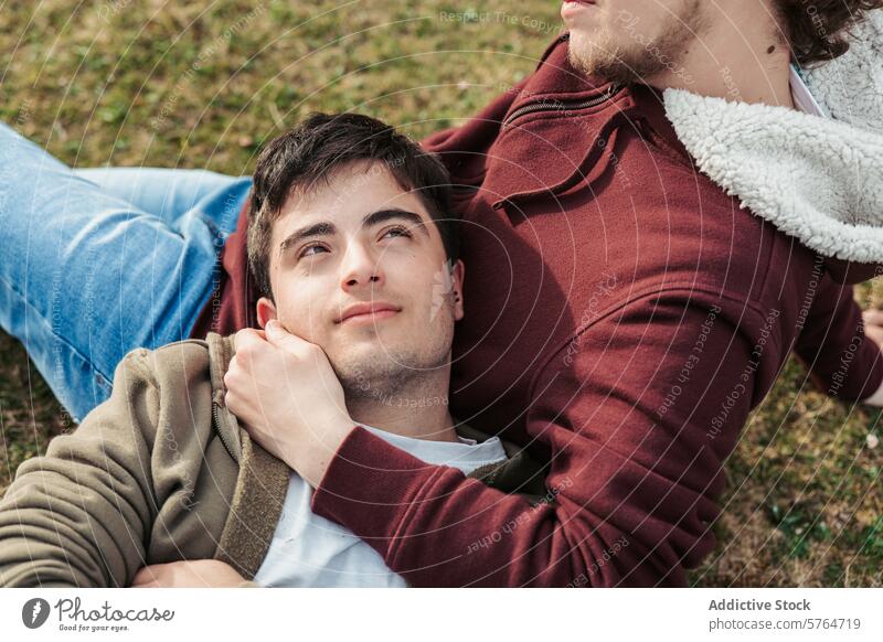 An intimate perspective of a man looking up adoringly while lying in his partner's arms, feeling safe and loved in a gentle embrace gaze gay affection outdoor