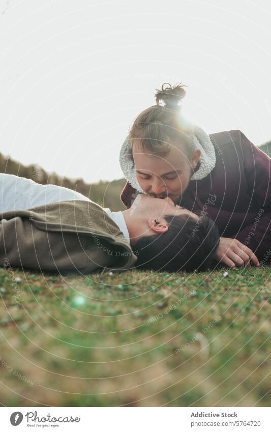 With the gentle light of dusk enveloping them, one man kisses his partner's forehead in a peaceful, grassy setting, a picture of love and tenderness men outdoor