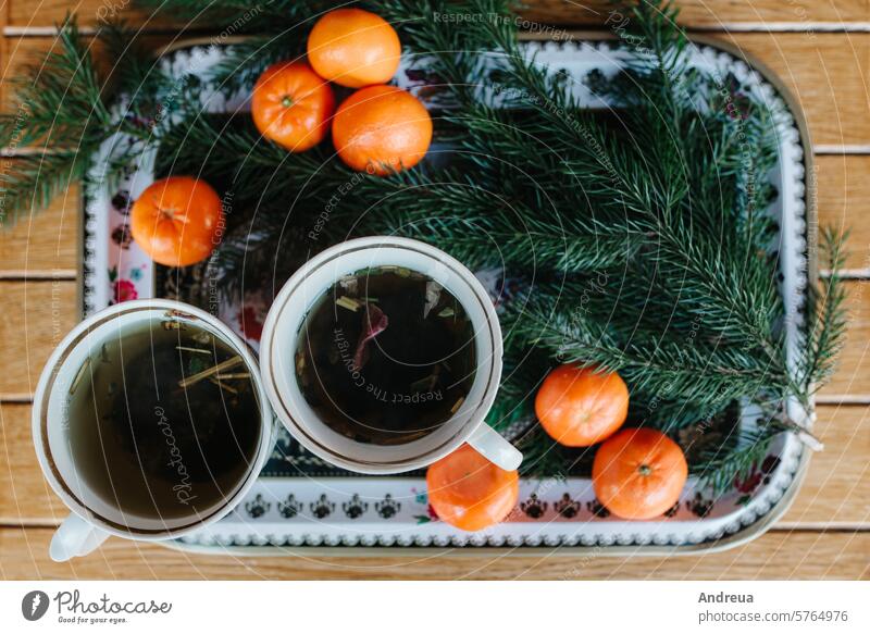 two cups of herbal tea on a table with tangerines and a spruce branch black brown chalet christmas cold couple forever gray hats hot house log house love