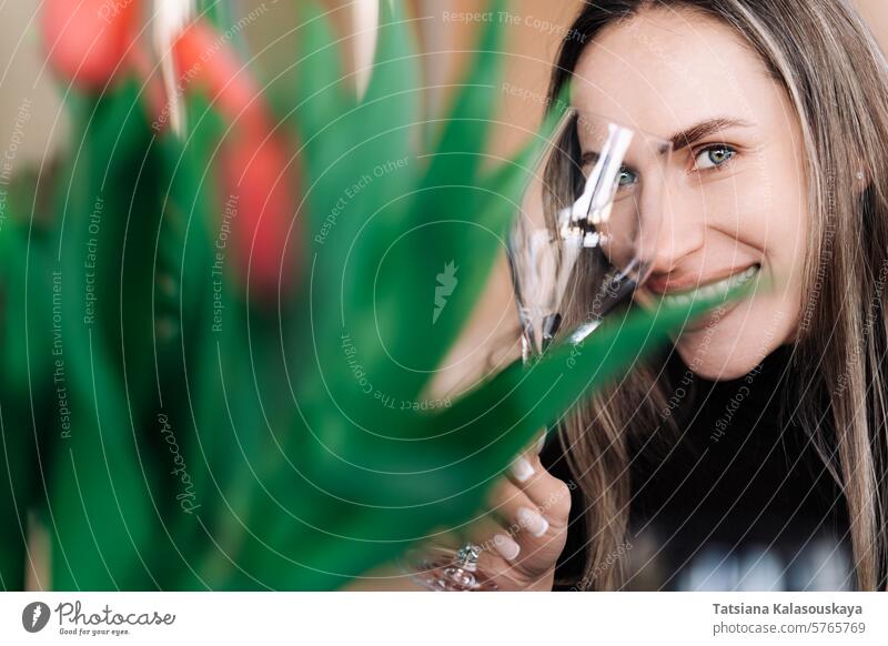 Happy woman looking at camera through glass wine glass while holding it in hand women springtime humor one woman only portrait drinking glass champagne bizarre