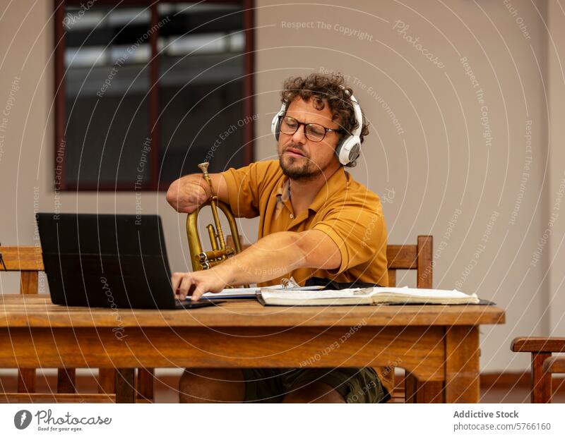 One-armed trumpeter composes music at home courtyard man male one-armed composition creative process work laptop notes focus musician disability adaptation