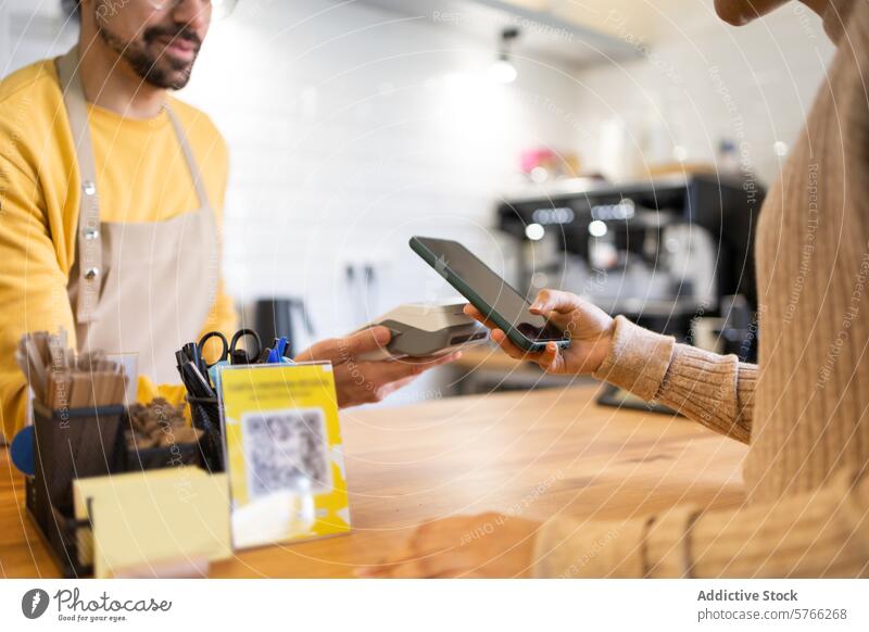 Customer making mobile payment at a modern cafe customer barista contactless smartphone checkout friendly technology transaction wireless digital apron service