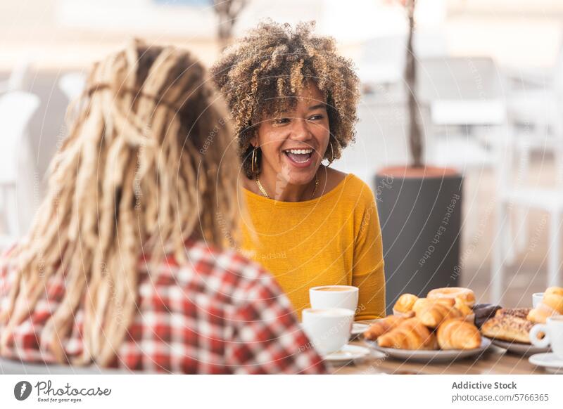 Friends sharing laughter over coffee and pastries friendship cafe conversation table joy enjoyment socializing leisure morning breakfast smiling casual clothing