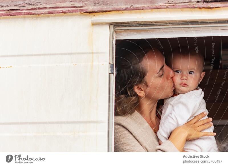 Van life family moment with mother kissing baby van life affection mobile home lifestyle nomadic bonding love camper simplicity minimalism doorway woman child