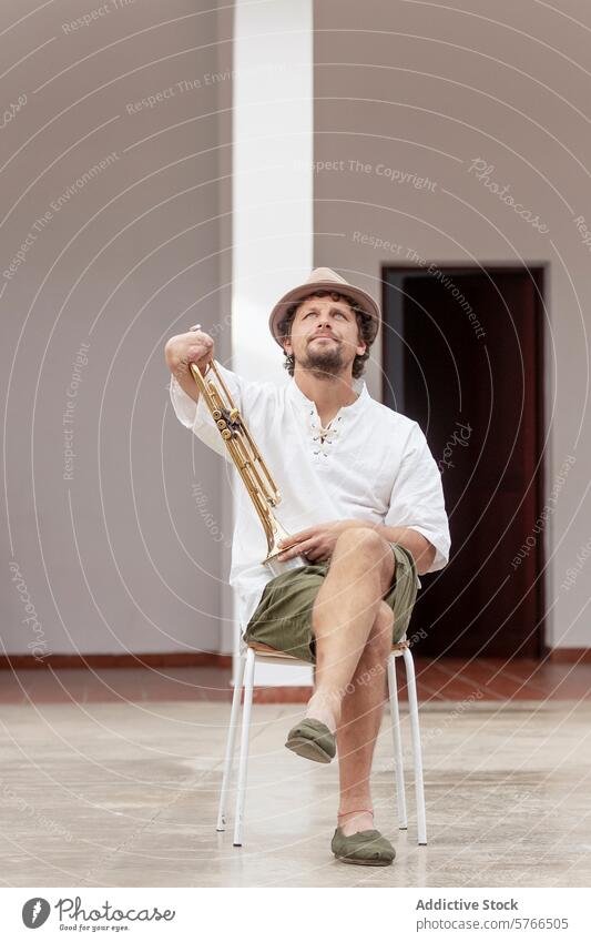 One-armed man holding trumpet, seated indoors one-armed sitting chair determination focus musical instrument brass practice home musician hobby adaptive