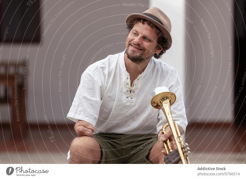Determined musician with trumpet at home one-armed smile man determination practicing passion sitting casual relaxed hat instrument brass hobby indoor ability