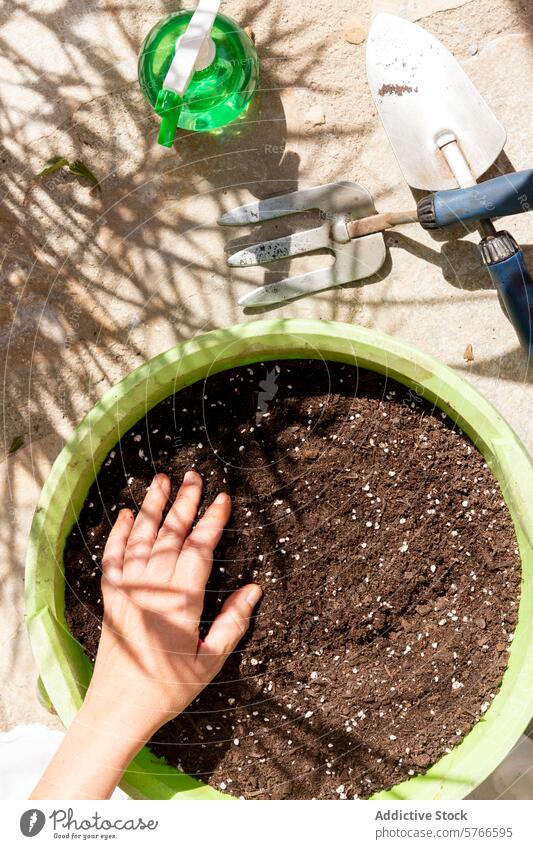 Preparing soil in a garden pot for planting gardening hand potting soil rich soil tools watering can green preparation outdoor sunlight shadow plant care