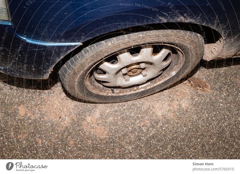 old, dirty tire of a car loses dry soil, the surrounding asphalt is dirty and dusty Car tire means of transport Dirty Dusty off the beaten track aridity Steppe