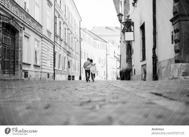 guy and a girl happily walk in the morning on the empty streets young hairstyle brown alone stone walls old fashionable europe joy counting emotions glasses