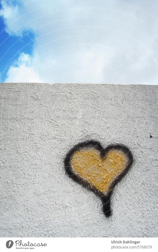 Heart graffiti, black border filled with gold, on a white wall with sky in the upper third Love Friendship Joy Graffiti fun Optimism Cordiality Spontaneity