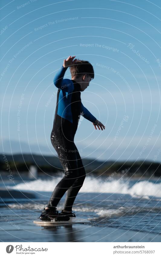 Boy in a wetsuit on a skimboard on the beach in the sea water in Sardinia Beach Italy Nature Water Sand Sandy beach vacation fun Family Surfer wave Ocean ocean