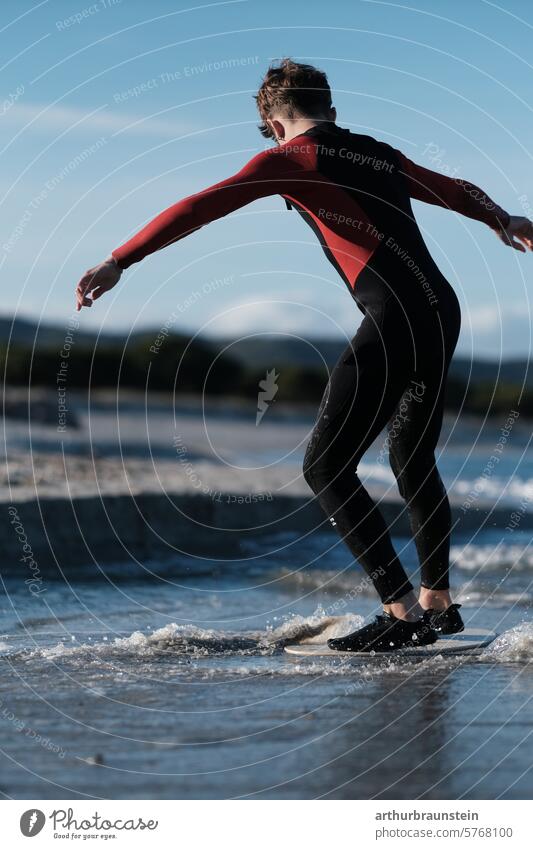 Boy in a wetsuit on a skimboard on the beach in the sea water in Sardinia Beach Italy Nature Water Sand Sandy beach vacation fun Family Surfer wave Ocean ocean