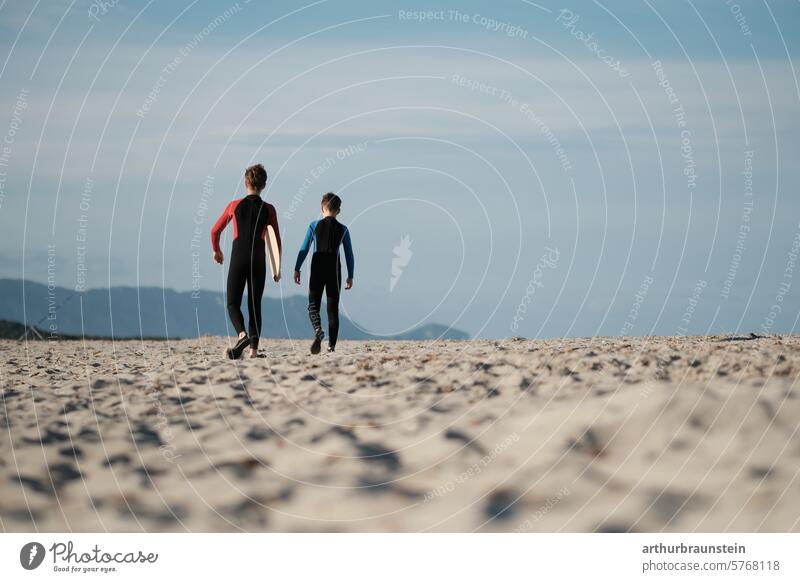 Young brothers in wetsuits with a skimboard on the beach in Sardinia on the way to the water Brothers Boy (child) Brothers and sisters Child Infancy children