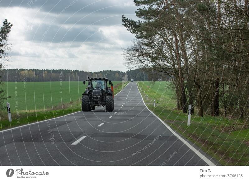 Tractor on two-lane country road Country road Spring Colour photo Agriculture Landscape Field Exterior shot Day Machinery