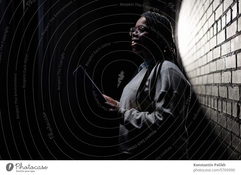 Minimal side view portrait of Black young woman rehearsing on stage in theater with low light copy space artist performer actor Black woman Black man read