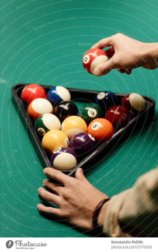 Minimal closeup of unrecognizable man holding red billiard ball while playing pool at green table copy space close up hand game bar billiard table snooker
