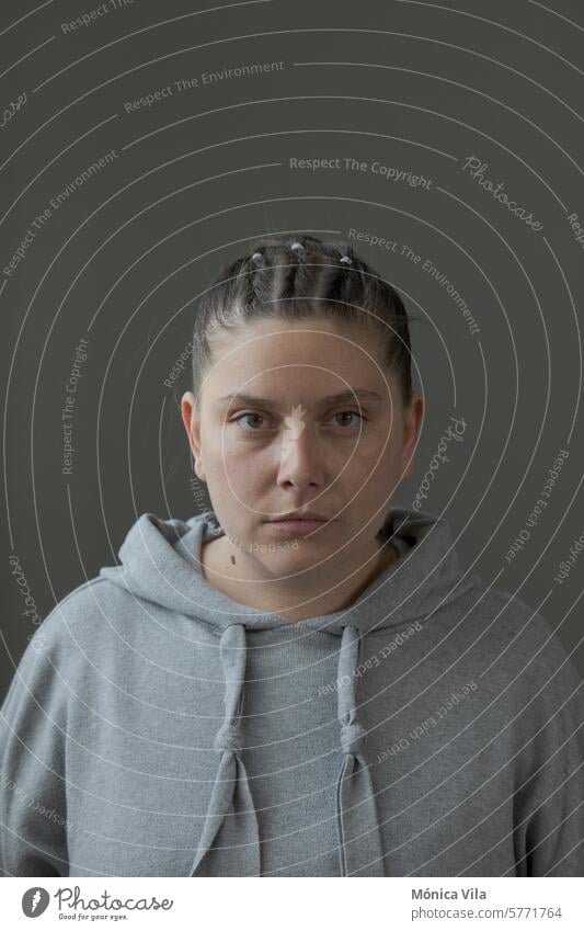 Vertical portrait with a gray background of a young goat with her hair up and wearing a gray sweatshirt. serious expression woman vertical gray color polka dot