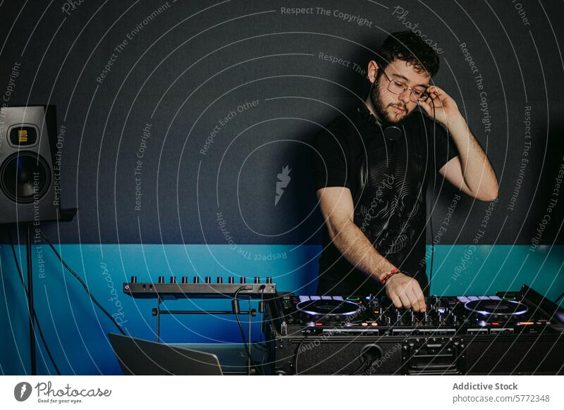 Concentrated DJ adjusting sound equipment at a club male young mixer dark headphones concentrating setting music entertainment performance turntable deck audio
