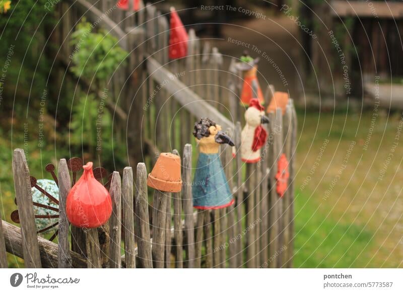 fence stool. various clay figures on the fence slats of a garden fence. decorations. Fence Do pottery laths Wooden fence variegated Decoration Exterior shot