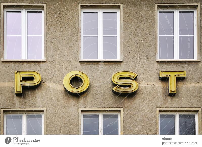 POST is written in dilapidated yellow neon letters on the old post office building Mail Neon sign Post office building Window Past Transience Decline Nostalgia
