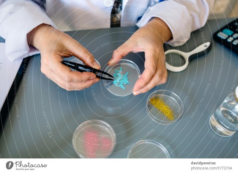 Unrecognizable female chemist technician examining blue glitter in facial cream sample on laboratory unrecognizable analyzing micro plastic microplastics