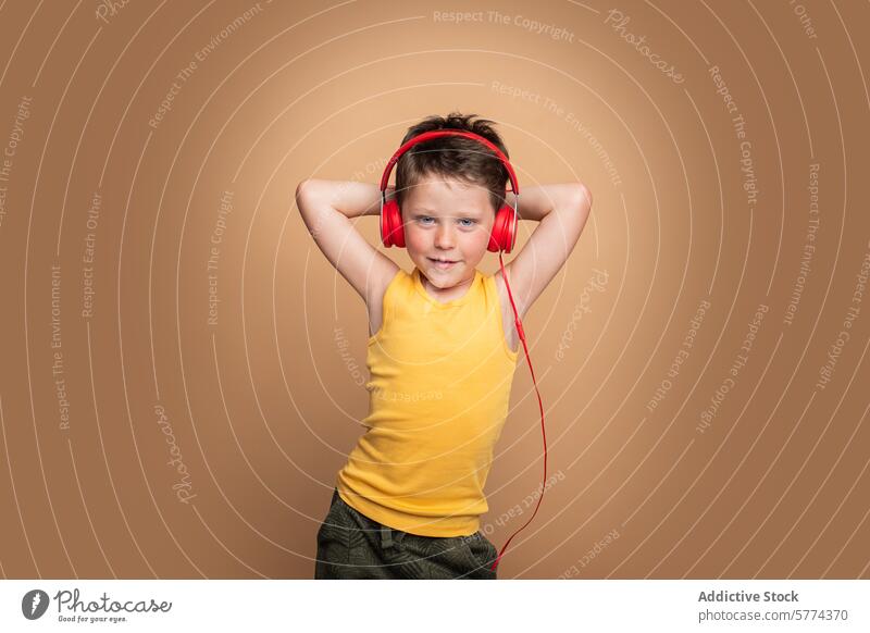 Young boy enjoying music with red headphones child smile yellow entertainment listening posing confident background brown tank top vibrant happy enjoyment