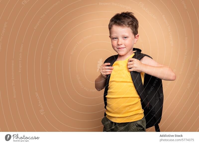 Young boy with a backpack ready for school child student education confident smiling young beige background schoolboy childhood casual pose cheerful happy