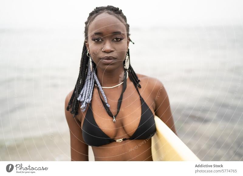 Serene African American Woman Standing by the Ocean woman african american beach serene calm black bikini braided hair surfboard ocean confidence ethnic