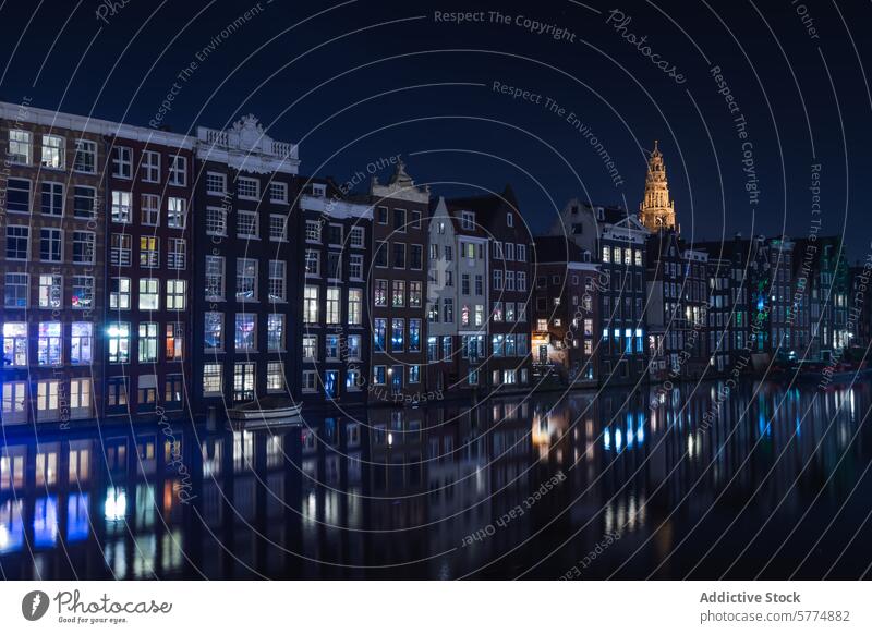 Amsterdam's Canal Houses at Night with Illuminated Windows amsterdam night canal house reflection water window illumination tower building historic architecture