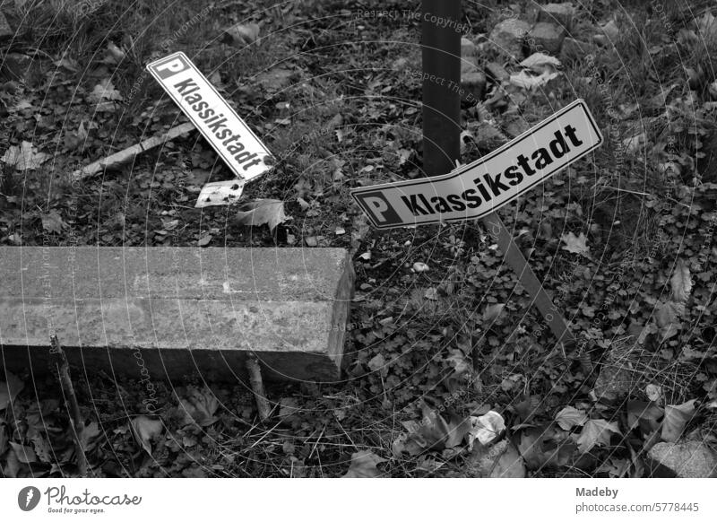 Old torn out tin signs and information signs in the green area next to the parking lot in the Klassikstadt in the Fechenheim district of Frankfurt am Main in Hesse in classic black and white