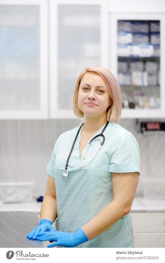 Vertical portrait of beautiful female doctor during appointment of patient in office a modern clinic. Skillful veterinarian is at the workplace in vet hospital. Woman looking at camera