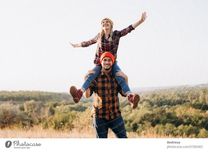 Cheerful guy and girl on a walk in bright knitted hats fun grass earth nature evening at sunset orange red love together together forever happiness family