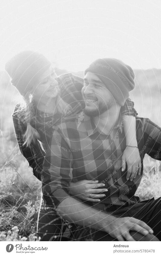 Cheerful guy and girl on a walk in bright knitted hats fun grass earth nature evening at sunset orange red love together together forever happiness family