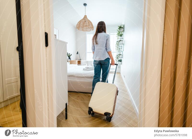 Rear view of a young woman entering a hotel room with her luggage suitcase packing clothing vacations travel preparation people one person bag tourism traveler
