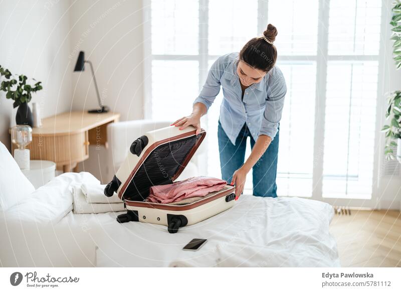 Young woman packing suitcase in the bedroom, preparing for travel clothing vacations preparation people luggage one person bag tourism traveler tourist adult