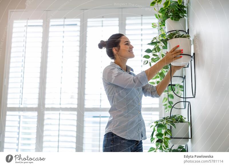 Woman taking care of the plants at her apartment woman people one person room living room adult young young adult indoors lifestyle happy smiling real people