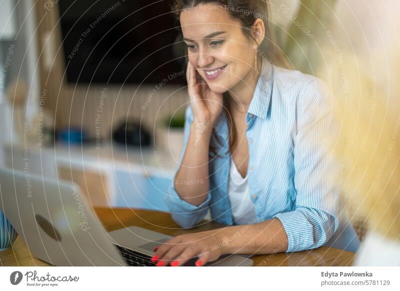 Young woman working on laptop at home people one person room living room adult young young adult indoors apartment lifestyle happy smiling real people beautiful