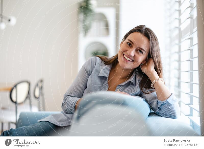 Portrait of a smiling young woman sitting on sofa at home people one person room living room adult young adult indoors apartment lifestyle happy real people