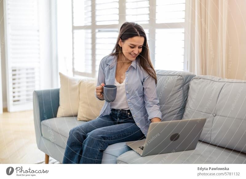Young woman working on laptop at home people one person room living room adult young young adult indoors apartment lifestyle happy smiling real people beautiful