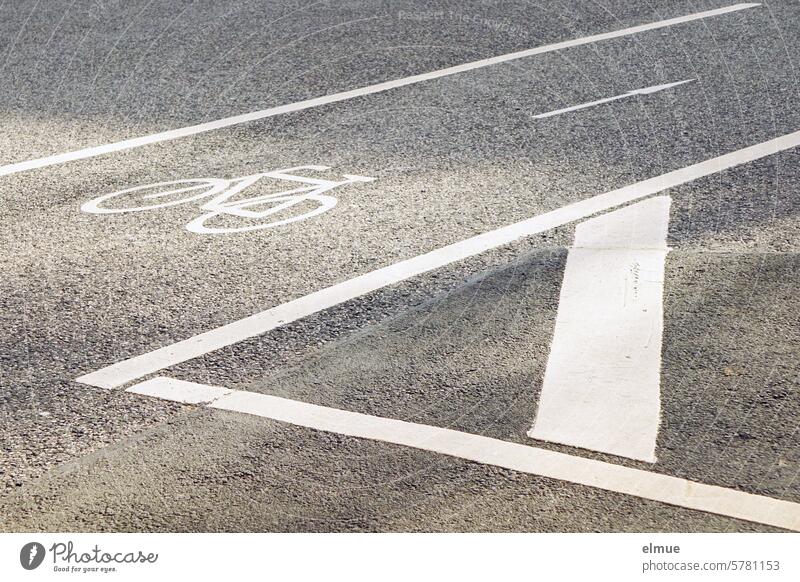 White cycle path marking with pictogram of a bicycle and arrow on gray asphalt Asphalt Street Ride a bike! Cycling wheel track Pictogram Road traffic